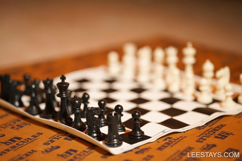 A chessboard with black and white pieces on a wooden table, reflecting leisure activities at Diamond Resort near Pawna Lake.