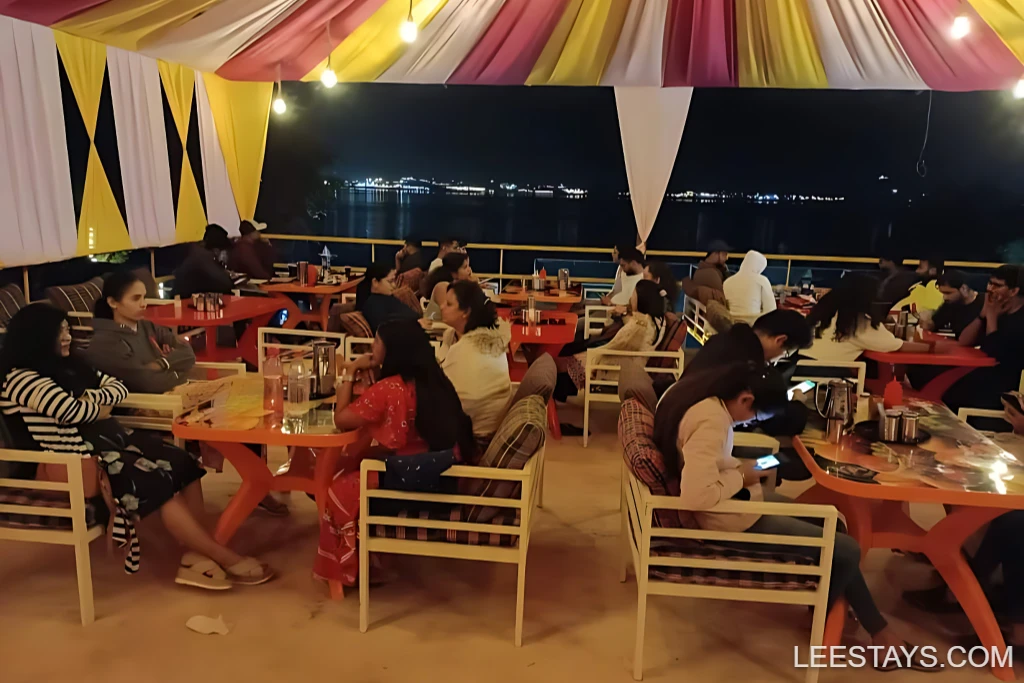 Guests enjoying a lively atmosphere at Diamond Resort, overlooking Pawna Lake at night with colorful decor and illuminated ambiance.