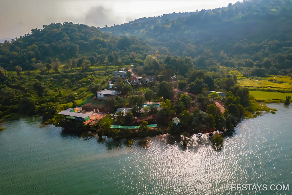 Aerial view of Diamond Resort located by Pawna Lake, surrounded by lush greenery and rolling hills, featuring serene waters and scenic landscapes.
