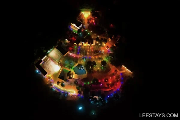 Aerial view of Diamond Resort near Pawna Lake, featuring vibrant multicolored lights and a landscaped area with various amenities.