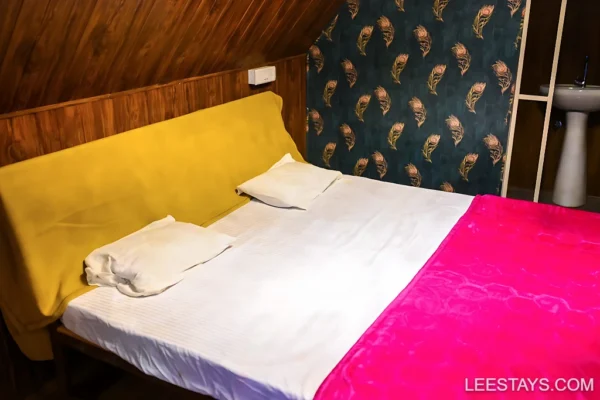 A cozy room at Diamond Resort near Pawna Lake, featuring a double bed with colorful linens and a decorative wall design.