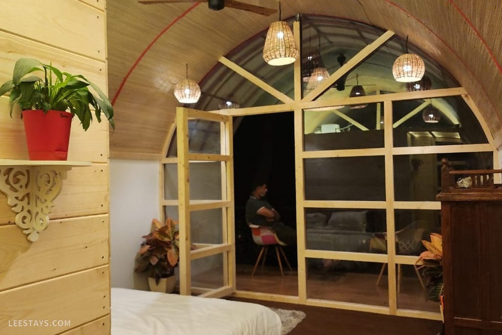 Stylish interior of a Resort in Kamshet, featuring wooden walls, decorative lighting, and a cozy atmosphere with greenery.
