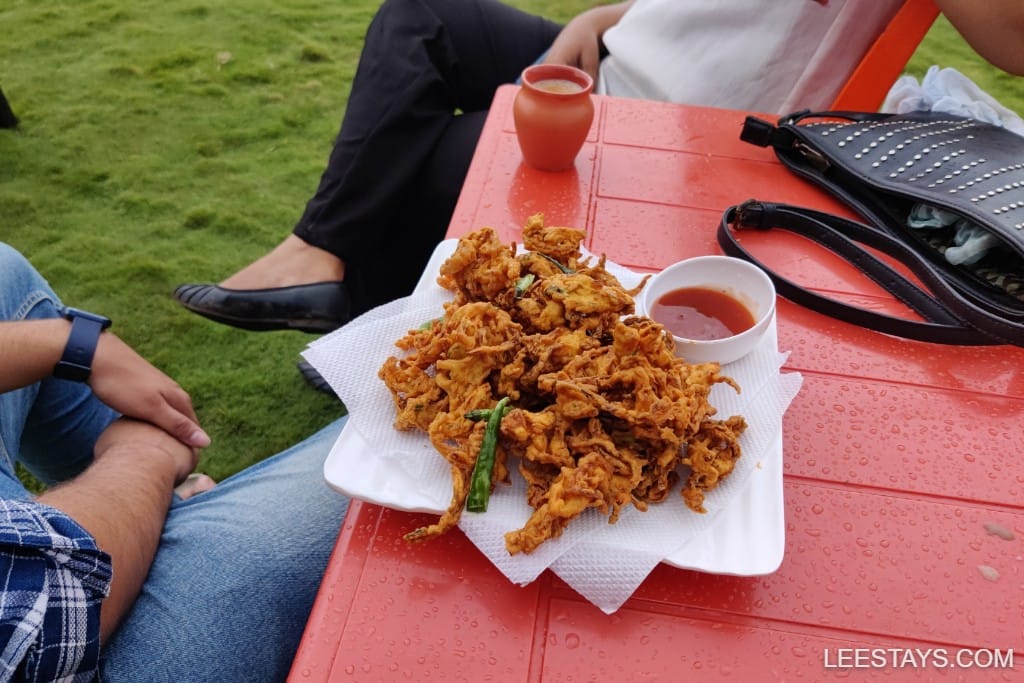 Delicious crispy fritters served with chutney, enjoyed during a stay at Pawna Lake, with drinks in the background.