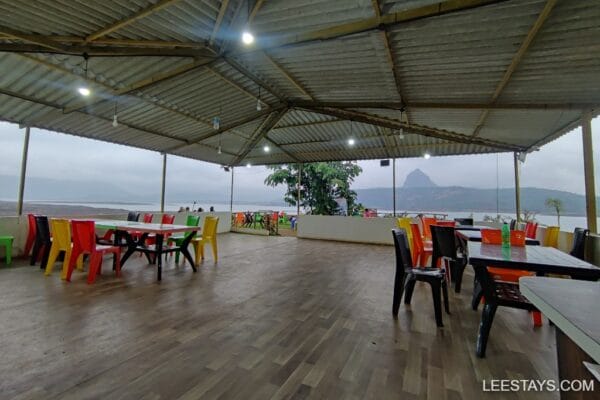 Vibrant seating area overlooking Pawna Lake, with colorful chairs and serene views of the water and mountains.