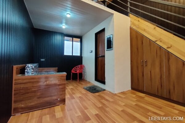 Cozy interior space with wooden flooring, a cushioned seating area, and a vibrant chair, perfect for a stay by Pawna Lake.