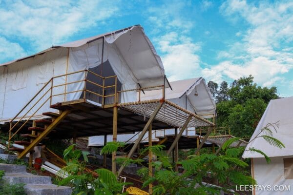 Stylish glamping accommodations near Pawna Lake, featuring elevated platforms and scenic surroundings under a bright sky.