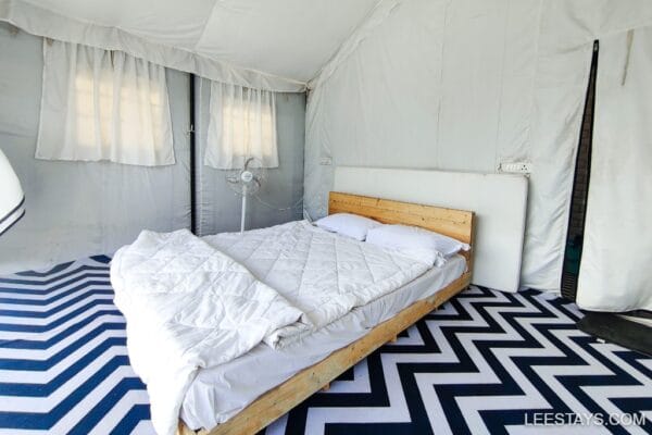 Cozy glamping setup at Pawna Lake featuring a spacious bed and stylish chevron-patterned floor, perfect for a relaxing getaway.