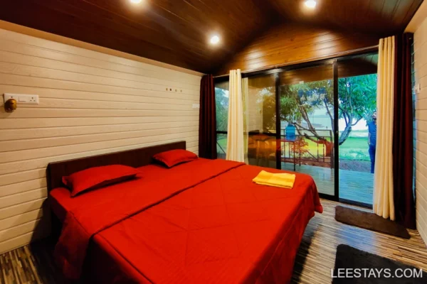 Cozy cottage interior with a red bed, overlooking Pawna Lake, perfect for a family getaway, surrounded by nature.