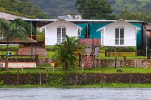 Charming cottages by the Pawna River, featuring lush greenery and scenic views, accompanied by a staircase leading to the waterfront.