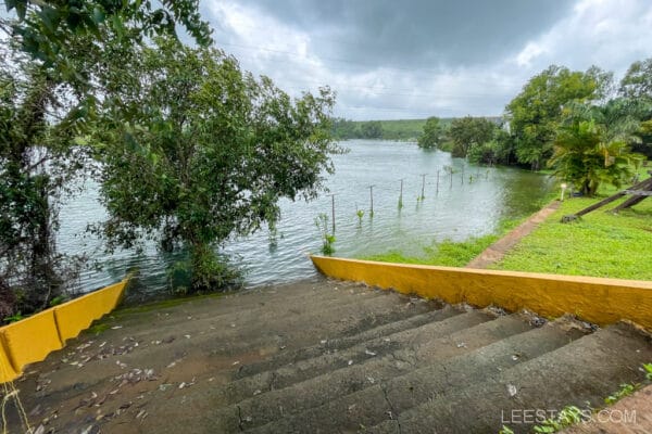 A serene view from a cottage near the Pawna River, with lush greenery and steps leading down to the water's edge.