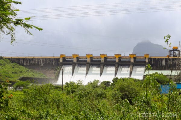 Scenic view of a dam with water flowing, surrounded by lush greenery near Cottage by the Pawna River.