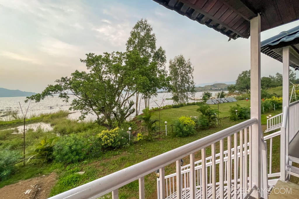View from a cottage overlooking Pawna Lake, with lush greenery, ideal for a couple seeking a serene retreat, and tents visible in the background.