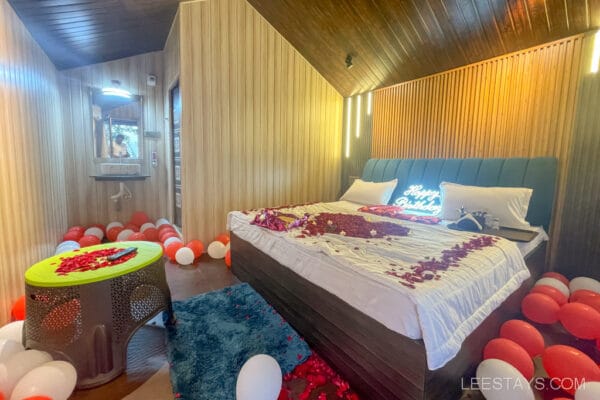 Romantic cottage near Pawna Lake decorated for a couple's celebration with rose petals on the bed, balloons, and a 'Happy Birthday' sign.