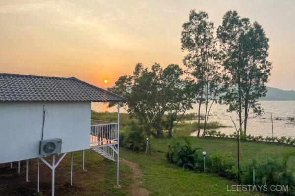 A lakeside cottage near Pawna Lake, with a view of trees and a sunset, ideal for a couple getaway.