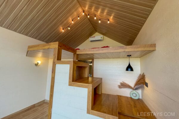 A cozy, modern loft space with wooden interiors, highlighting glass rooms near Pawna Lake, featuring ambient lighting and contemporary decor.